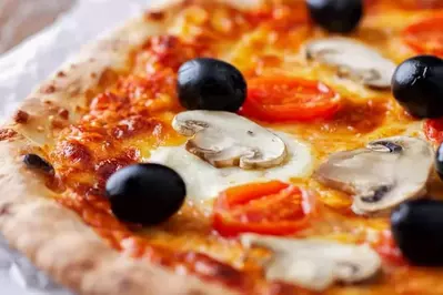 Closeup of pizza with mushrooms, tomatoes, and black olives.