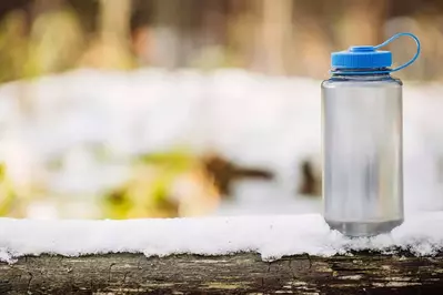 water bottle sitting on a snowy log 