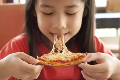 little girl enjoying a slice of pizza