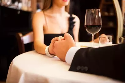 A couple holding hands at a romantic dinner in a restaurant.