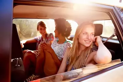 Three women in the back of a car on a road trip.