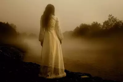 A female ghost standing by the water.