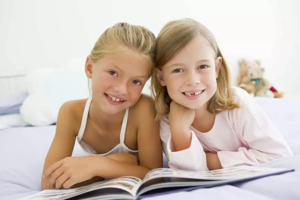 Two girls reading a book on a sleepover.