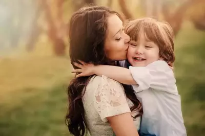 A mother kissing her young son.