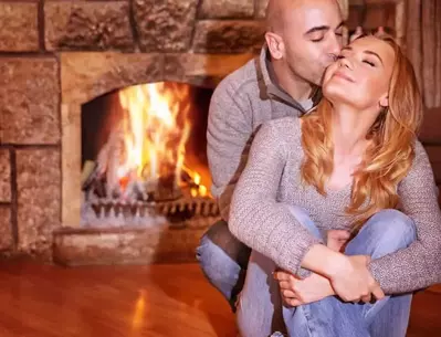 A happy couple embracing in front of the fireplace in their cabin.