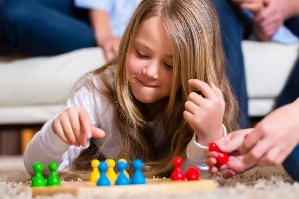 Little girl playing a board game with her family.