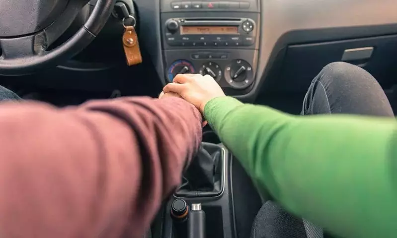 Couple holding hands in the car in Cades Cove